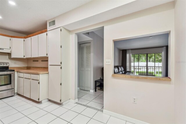 kitchen featuring light tile patterned floors, white cabinetry, and stainless steel range with electric cooktop