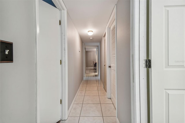 hall featuring baseboards and light tile patterned floors