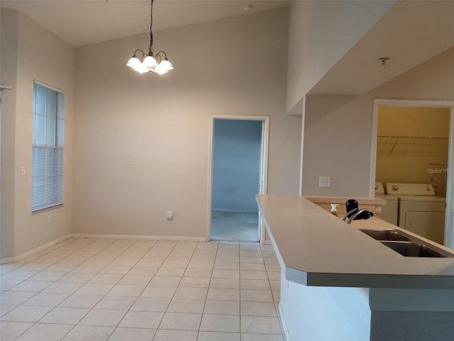 kitchen with high vaulted ceiling, a chandelier, washing machine and dryer, hanging light fixtures, and light tile patterned flooring