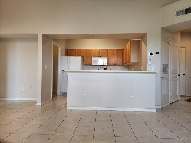 kitchen featuring kitchen peninsula, white appliances, and light tile patterned flooring