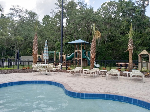 view of swimming pool with a playground and a patio