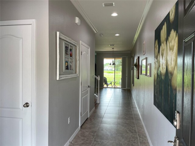 hall featuring dark tile patterned flooring and crown molding