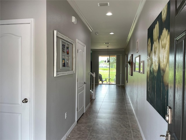 hallway with baseboards, visible vents, and crown molding