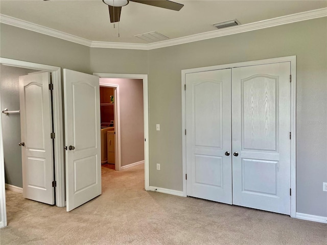 unfurnished bedroom with ceiling fan, light colored carpet, a closet, and crown molding