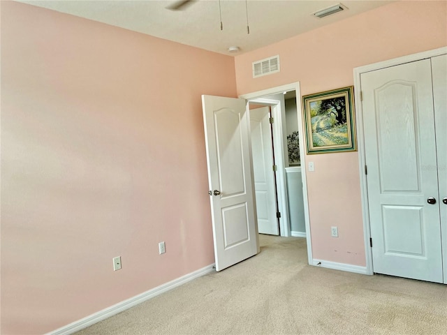 unfurnished bedroom featuring light carpet, visible vents, and baseboards