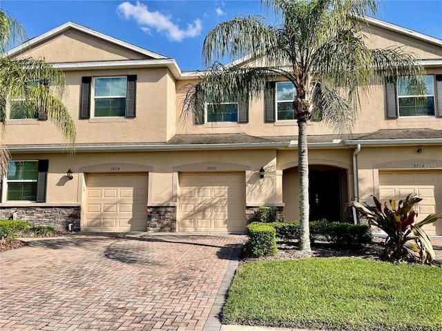 multi unit property featuring stucco siding, an attached garage, and driveway