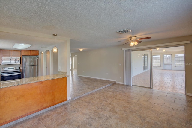 kitchen featuring light stone countertops, pendant lighting, appliances with stainless steel finishes, a textured ceiling, and ceiling fan