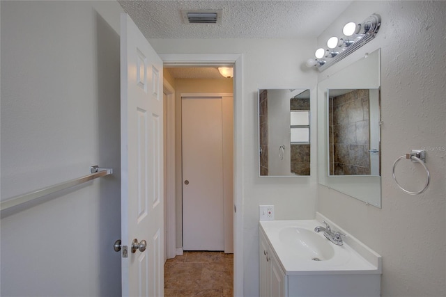 bathroom with a textured ceiling, tile patterned floors, and vanity