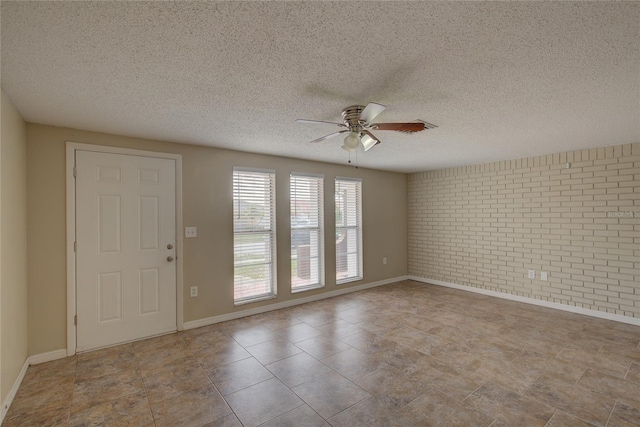 spare room with ceiling fan, brick wall, and a textured ceiling