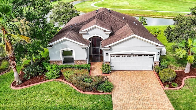 view of front facade with a front yard, a water view, and a garage