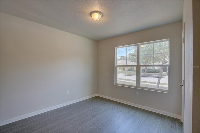 spare room featuring dark hardwood / wood-style flooring and a textured ceiling