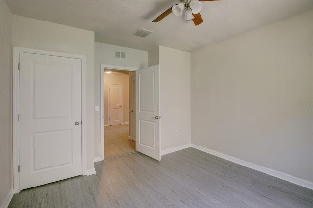 unfurnished bedroom featuring ceiling fan, light hardwood / wood-style floors, and a textured ceiling