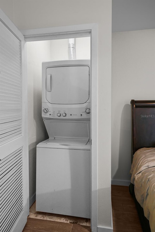 washroom with dark wood-type flooring and stacked washer and dryer