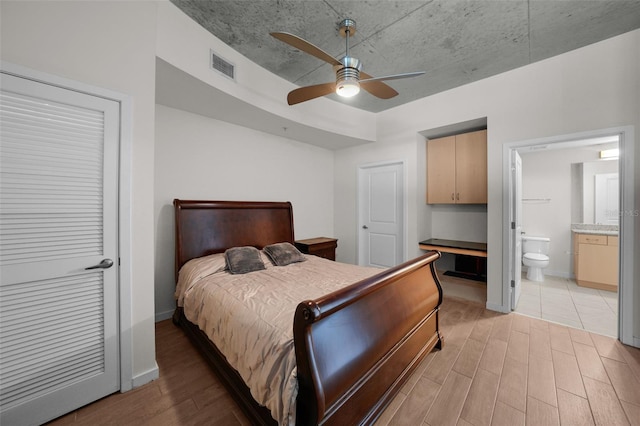 bedroom featuring ceiling fan, light hardwood / wood-style floors, and ensuite bath