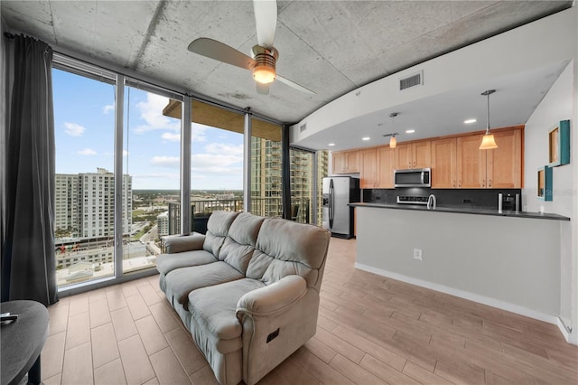 living room featuring floor to ceiling windows, ceiling fan, and light wood-type flooring