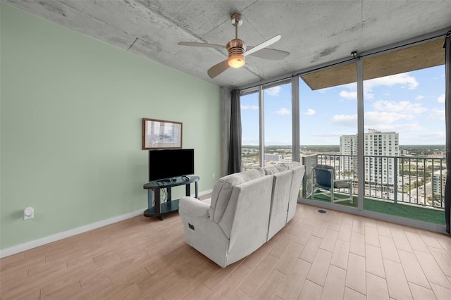 living room featuring a wall of windows, light hardwood / wood-style floors, and ceiling fan