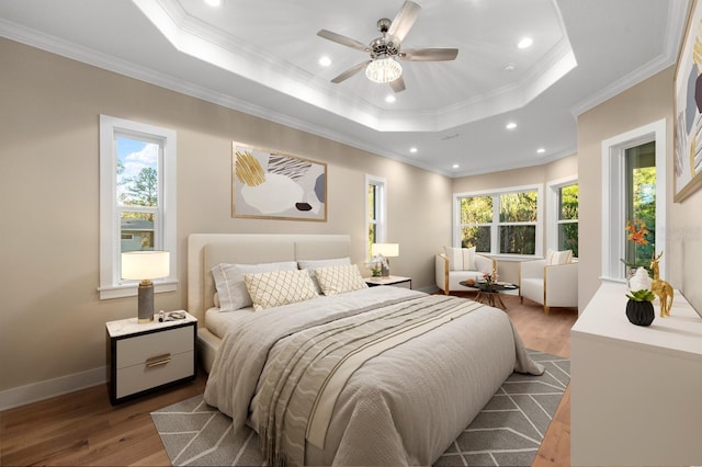 bedroom with ornamental molding, a tray ceiling, ceiling fan, and hardwood / wood-style flooring