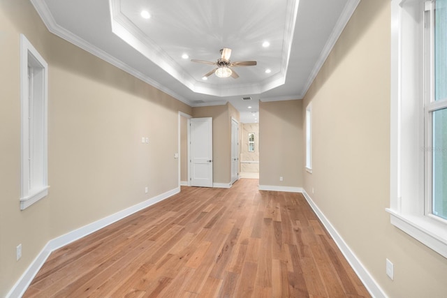 unfurnished room featuring a raised ceiling, ceiling fan, light wood-type flooring, and ornamental molding