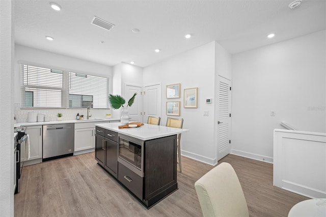 kitchen featuring white cabinets, sink, light hardwood / wood-style flooring, appliances with stainless steel finishes, and a kitchen island