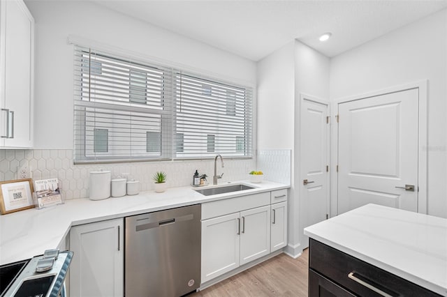 kitchen featuring dishwasher, backsplash, sink, light hardwood / wood-style floors, and white cabinetry