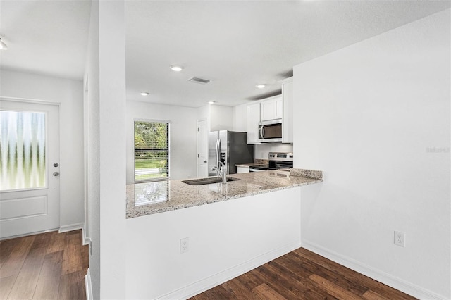 kitchen with light stone countertops, appliances with stainless steel finishes, dark hardwood / wood-style flooring, sink, and white cabinetry