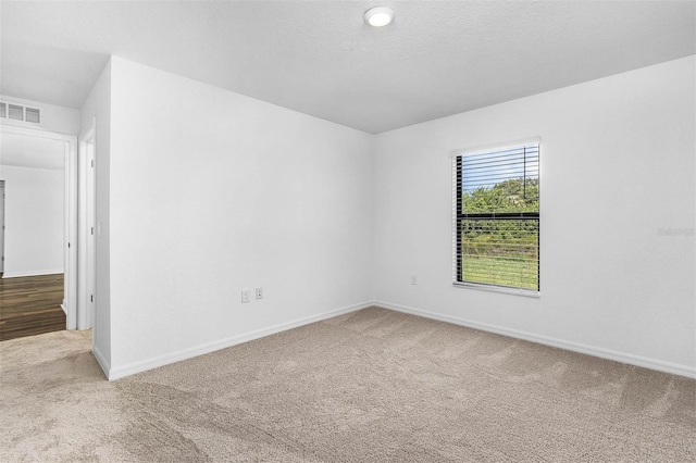 carpeted empty room with a textured ceiling