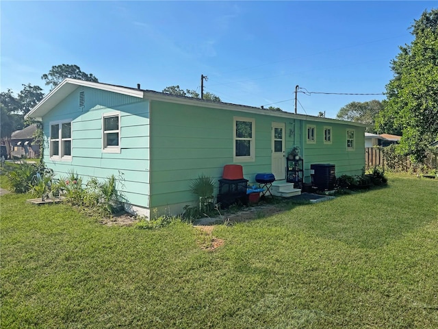 back of property with a yard and central air condition unit