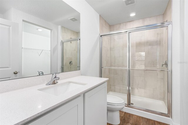 bathroom with a shower with shower door, hardwood / wood-style flooring, toilet, and vanity