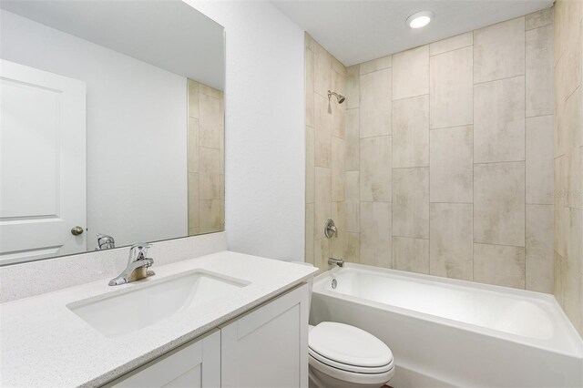 full bathroom featuring vanity, tiled shower / bath combo, and toilet