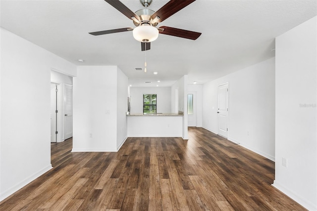 unfurnished living room featuring dark wood-type flooring and ceiling fan