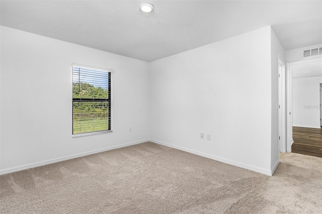 carpeted empty room featuring a textured ceiling