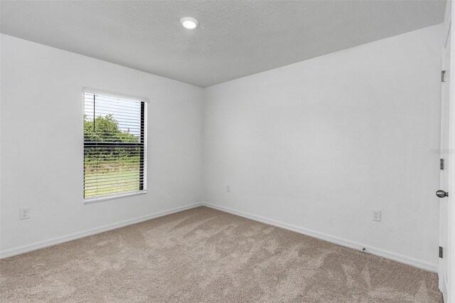 carpeted empty room with a textured ceiling