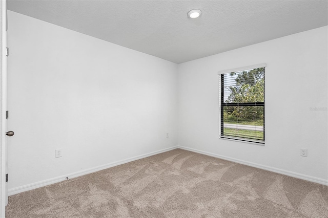 empty room with a textured ceiling and carpet flooring