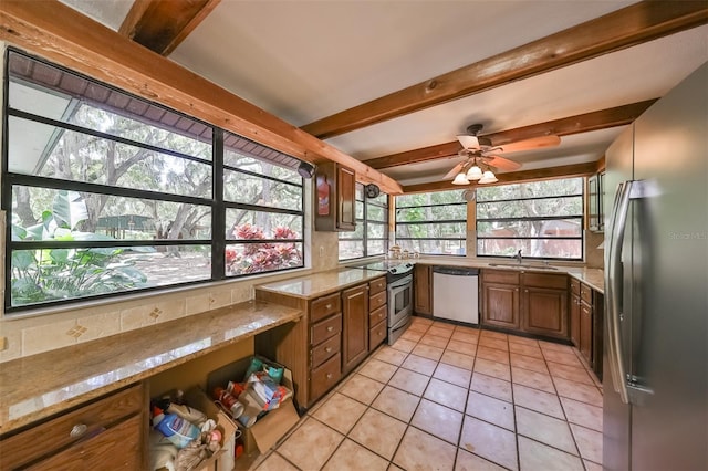 kitchen with appliances with stainless steel finishes, sink, light tile patterned floors, light stone counters, and beam ceiling