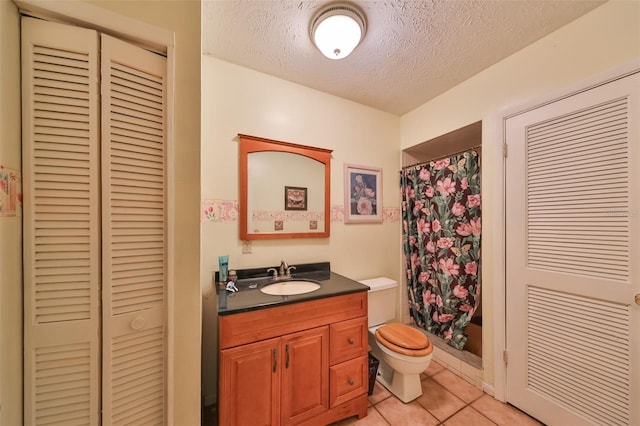 bathroom featuring vanity, toilet, tile patterned flooring, and a textured ceiling