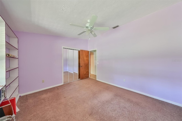 unfurnished bedroom featuring a textured ceiling, carpet floors, a closet, and ceiling fan