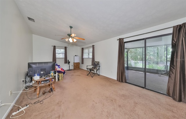 sitting room featuring ceiling fan, lofted ceiling, carpet flooring, and a textured ceiling