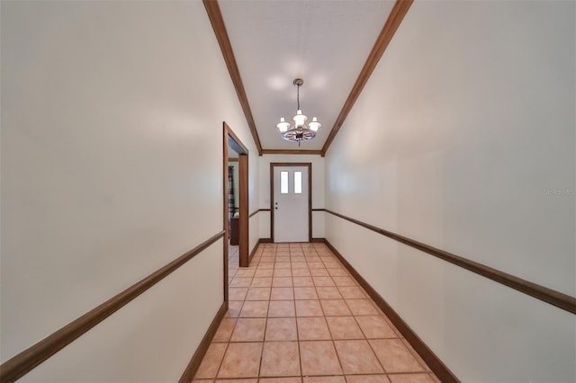 doorway to outside featuring light tile patterned flooring, ornamental molding, and a notable chandelier