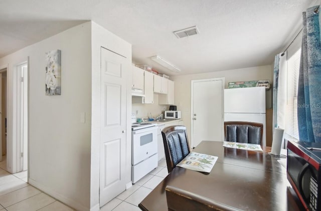 kitchen with white cabinets, white appliances, and light tile patterned flooring