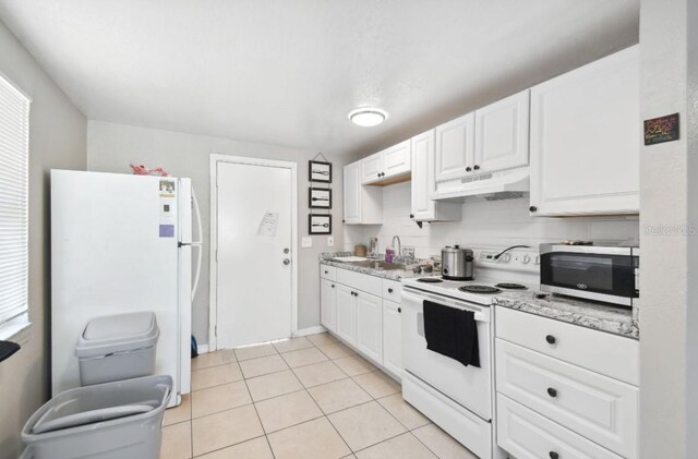 kitchen with white appliances, sink, light tile patterned floors, light stone counters, and white cabinetry