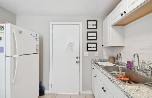 kitchen with light stone countertops, sink, light tile patterned floors, white refrigerator, and white cabinets