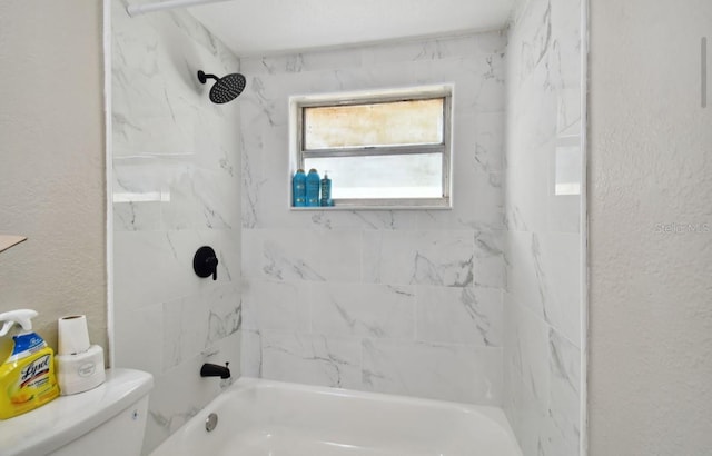 bathroom featuring tiled shower / bath combo and toilet