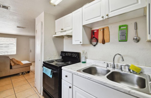 kitchen with light tile patterned floors, electric range, white cabinetry, and sink