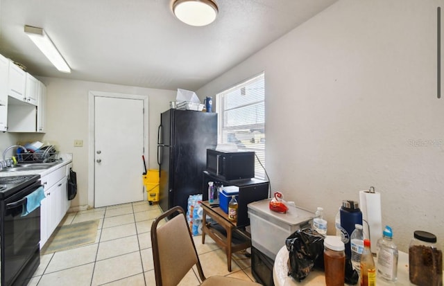 kitchen featuring light tile patterned floors, white cabinetry, black appliances, and sink