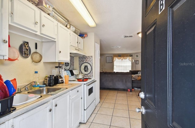 kitchen featuring white electric range oven, sink, white cabinetry, and light tile patterned flooring