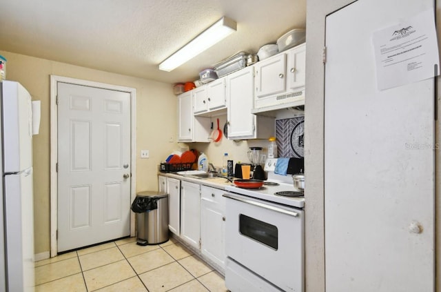 kitchen with a textured ceiling, light tile patterned floors, white cabinets, and white appliances