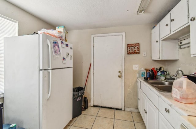 kitchen featuring white cabinets, white fridge, light tile patterned flooring, and a textured ceiling