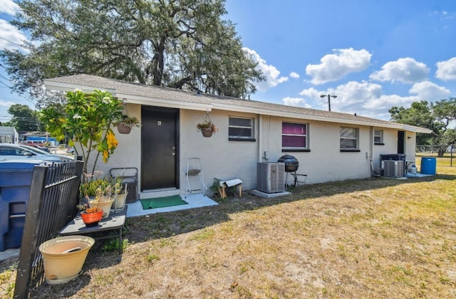 rear view of house with a yard and central AC unit