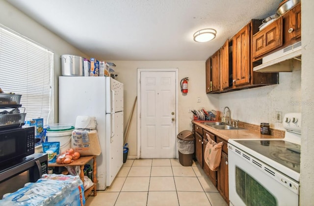 kitchen with light tile patterned floors, white appliances, a textured ceiling, and sink