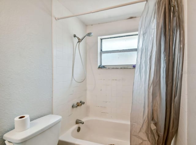 bathroom featuring toilet and shower / bathtub combination with curtain